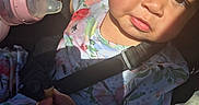 Sophia joined the competition — help win amazing prizes! toddler, child, baby_bottle, car_seat, seatbelt, floral_clothing, sunlight, shadow, hand, face, expression, snack, young_child, indoors, seat, person, cute, portrait, closeup, child_seat