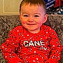 toddler, child, smile, red_sweater, candy_cane_pattern, stars, sitting, couch, indoor, happy, face, holiday, festive, young_child, portrait, clothing, cozy, cute, person, casual