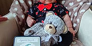 Ezio a rejoint le concours — aidez-le/la à gagner de superbes lots ! baby, black_pants, blanket, chair, child, clothing, cute, decor, heart_pattern, indoor, infant, milestone, person, plush_toy, portrait, red_bow_tie, sign, smiling, teddy_bear, text
