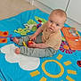 baby, blue_eyes, book, child, childrens_toy, clothing, colorful, curious, cute, floor, flooring, head, indoor, infant, person, play_mat, playtime, portrait, sitting, toy