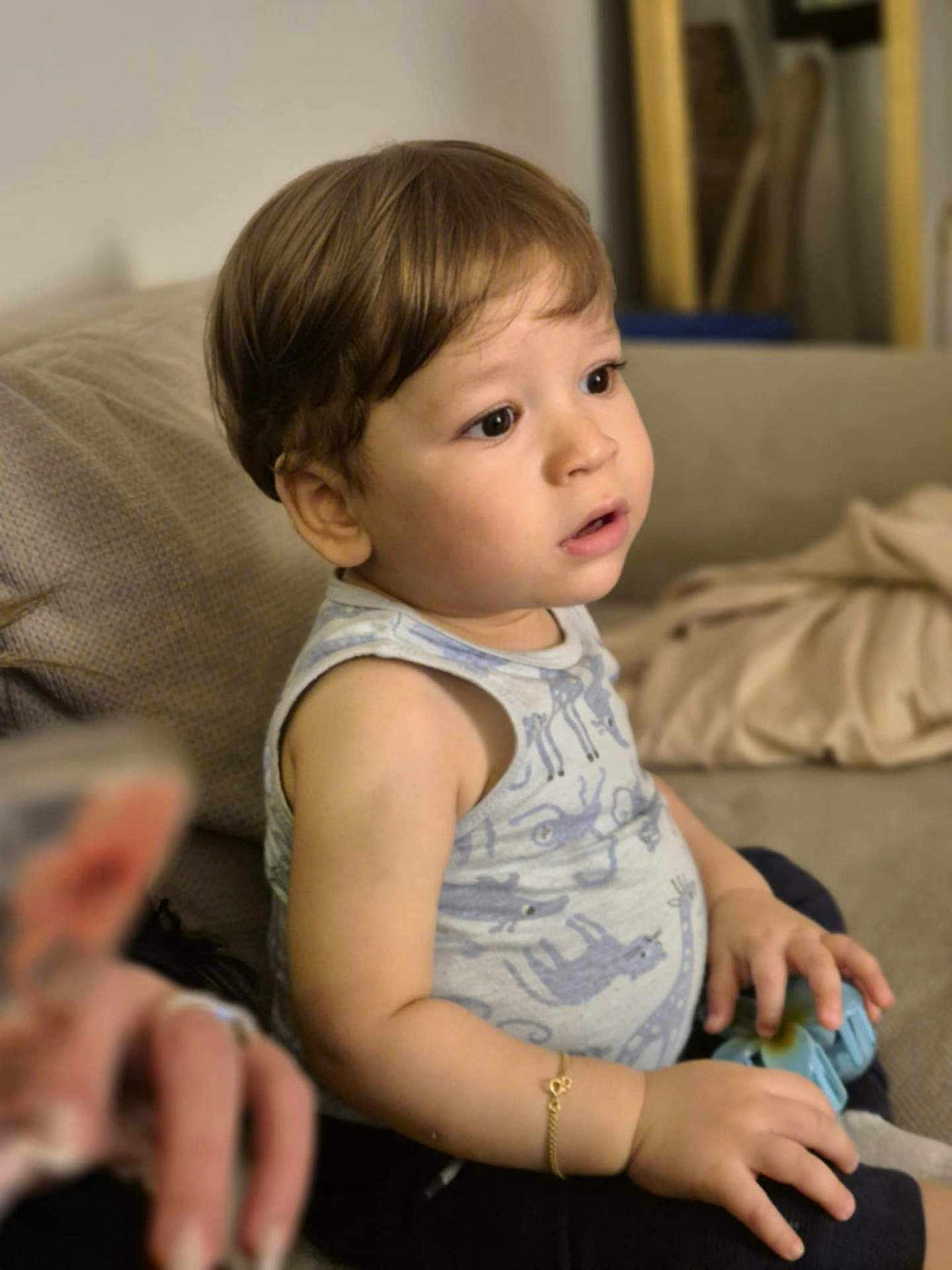 Mehdi participe au concours pour gagner de l'argent avec cette photo : toddler, child, indoor, couch, toy, bracelet, sleeveless_shirt, animal_print, brown_hair, curious, seated, soft_lighting, home, casual, young_child, portrait, attention, small_hands, furniture, relaxed