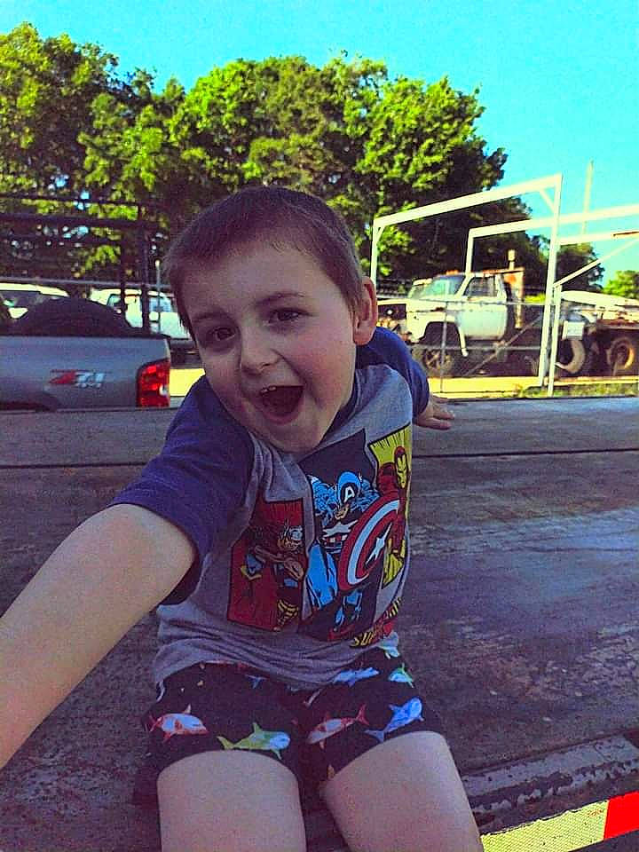 Aiden is registered to the contest to win money with this photo: asphalt, cool, eye, facial_expression, fun, hairstyle, happy, leaf, leisure, person, photograph, plant, public_space, sky, smile, standing, summer, sunlight, toddler, travel