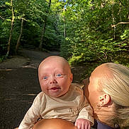 Rome is registered to the contest to win money with this photo: baby, child, woman, shoulder, forest, trees, sunlight, outdoor, nature, path, greenery, happy, smiling, person, skin, hair, earrings, clothing, daytime, scenery