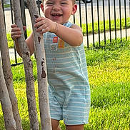 Noah is registered to the contest to win money with this photo: toddler, child, smiling, tree, grass, outdoor, sunlight, romper, happy, baby, fence, car, person, nature, greenery, daylight, portrait, playful, young_child, holding