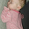 baby, sleeping, pajamas, striped_clothing, couch, pillow, indoor, child, face, peaceful, infant, rest, cozy, home, soft_lighting, portrait, young_child, cute, relaxing, comfort