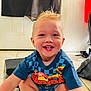 toddler, child, smiling, indoor, shorts, tshirt, blond_hair, happy, floor, tiles, door, curtain, step_stool, playful, crouching, person, young_child, casual_clothing, home, portrait