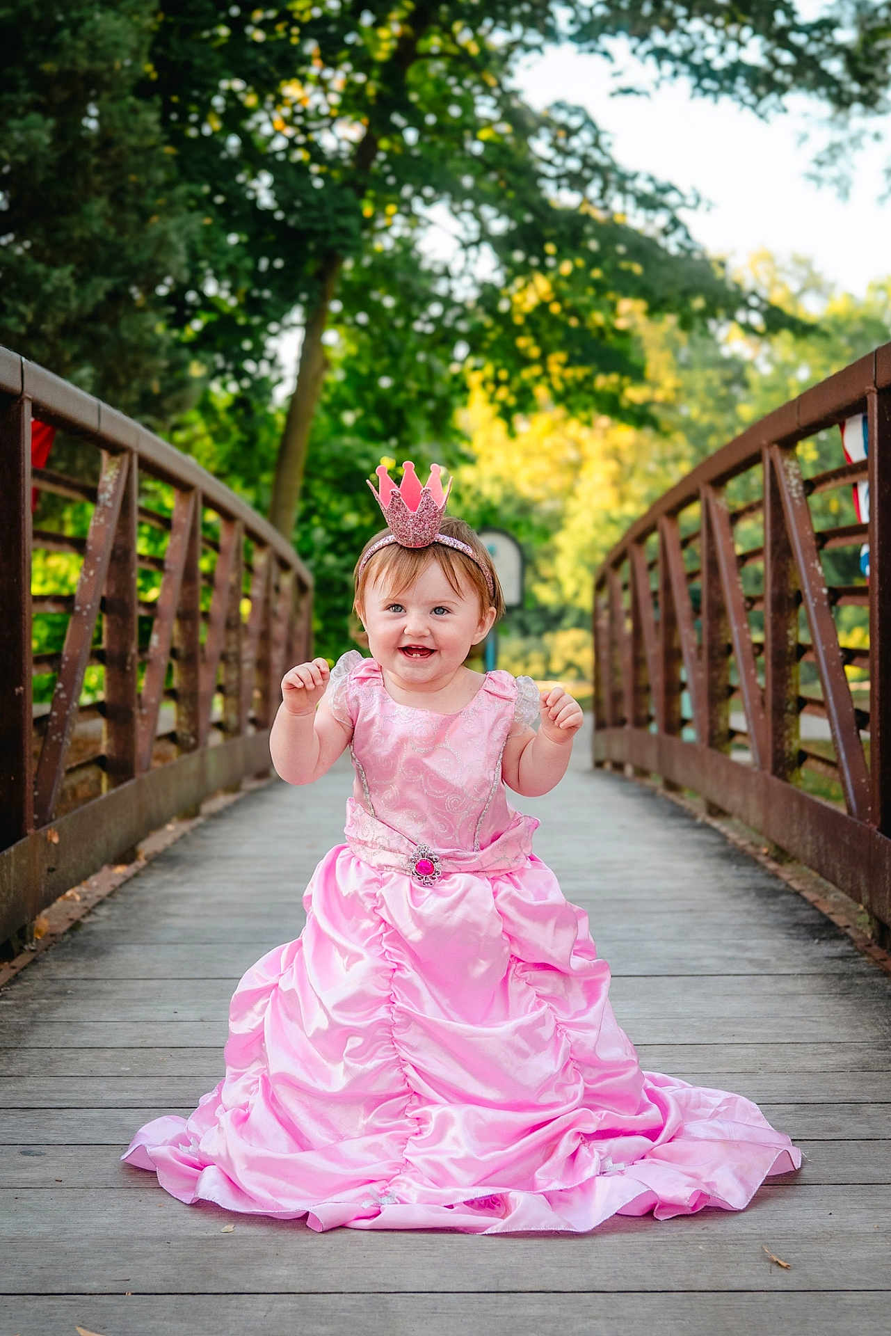 Paislyee joined the competition — help win amazing prizes! child, toddler, pink_dress, princess, crown, headband, bridge, wooden_bridge, outdoor, trees, greenery, happy, smiling, portrait, nature, daylight, cute, baby, person, fashion