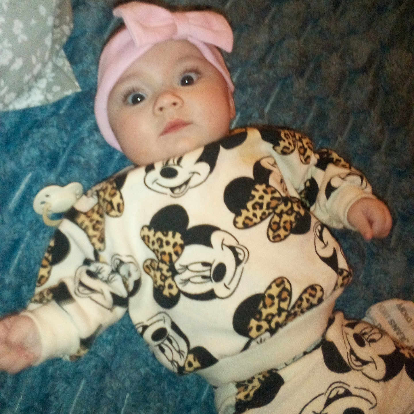 Nariah joined the competition — help win amazing prizes! baby, bed, blanket, bow, clothing, cute, face, headband, indoor, infant, laying_down, leopard_print, mickey_mouse, newborn, onesie, pacifier, pillow, portrait, surprised, wide_eyes