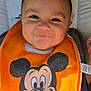 baby, baby_accessory, bib, car_seat, child, closeup, clothing, cute, fabric, face, happiness, indoor, infant, mickey_mouse, orange, person, portrait, seatbelt, smile, young_child