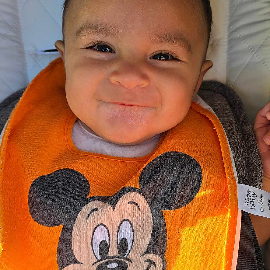 Qaelen joined the competition — help win amazing prizes! baby, baby_accessory, bib, car_seat, child, closeup, clothing, cute, fabric, face, happiness, indoor, infant, mickey_mouse, orange, person, portrait, seatbelt, smile, young_child