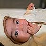 baby, infant, face, hand, hood, ears, clothing, cozy, cute, portrait, closeup, skin, eyes, indoors, soft_texture, warm_colors, sleepwear, child, person, lying_down