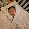 baby, blanket, sleeping, crib, pillow, plush_toy, soft_texture, cozy, infant, child, cute, resting, face, head, bed, nursery, comfort, warm, peaceful, indoors