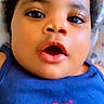 baby, child, face, curly_hair, blue_shirt, text, american_cutie, close_up, expression, infant, cute, portrait, skin, eyes, mouth, clothing, heart, person, young, indoors
