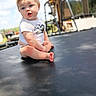 baby, child, toddler, sitting, trampoline, outdoor, backyard, sunlight, blue_sky, portrait, face, eyes, smiling, surprised, white_shirt, shorts, barefoot, playground, wooden_house, photography