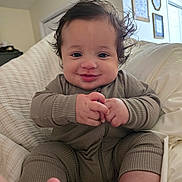 Myles is registered to the contest to win money with this photo: baby, infant, smiling, clothing, hands, face, hair, bed, blanket, indoors, person, cute, happy, onesie, foot, skin, portrait, child, room, wall_art