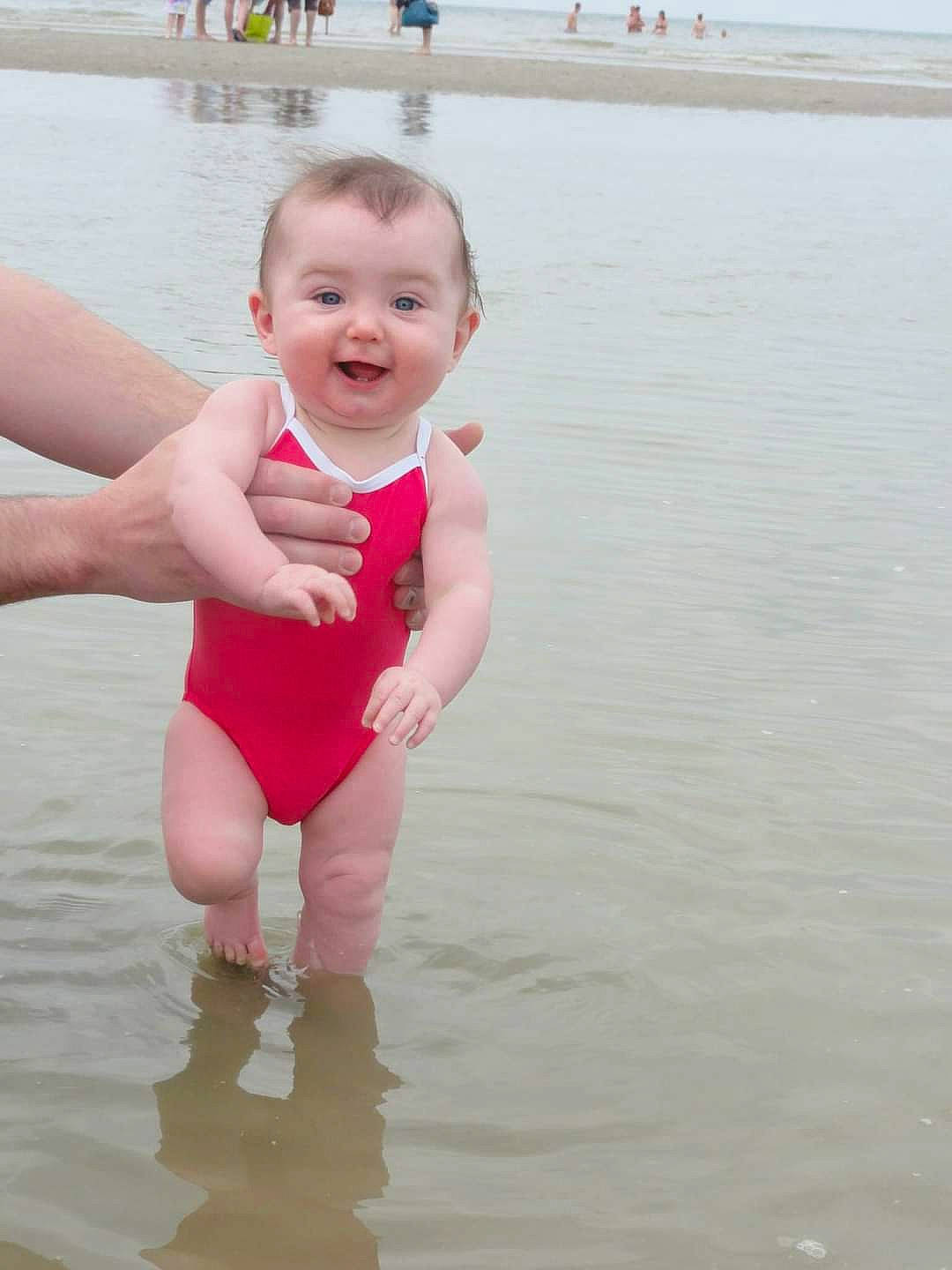 Mathilde a rejoint le concours — aidez-le/la à gagner de superbes lots ! bathing, beach, chest, face, fun, happy, joy, lake, leg, leisure, one_piece_swimsuit, people_on_beach, person, personal_protective_equipment, recreation, skin, smile, swimwear, thigh, toddler