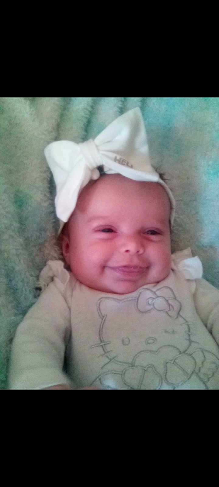 Serenity is registered to the contest to win money with this photo: baby, infant, bow, headband, onesie, hello_kitty, smile, smiling, cheeks, blanket, cozy, portrait, closeup, cute, hat, lying_down, baby_girl, nursery, soft_texture, happy