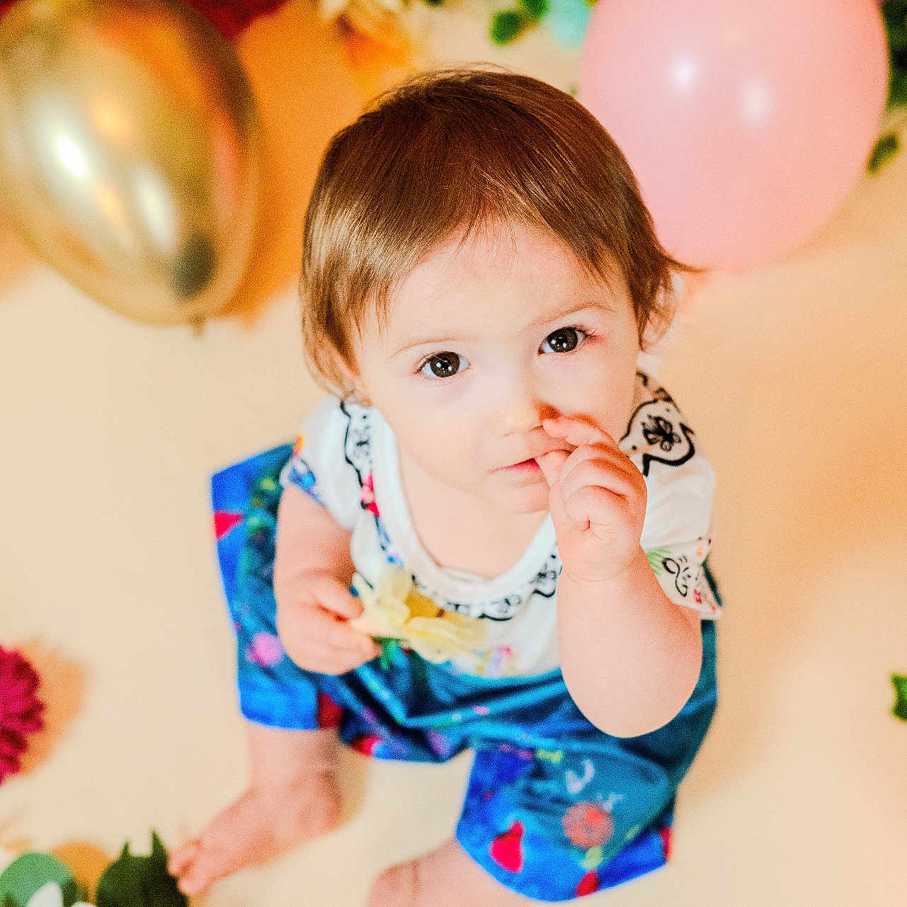Florencia participe au concours pour gagner de l'argent avec cette photo : baby, balloons, bright, celebration, child, clothing, colorful, curious, cute, decorations, flowers, happy, indoors, looking_up, playful, portrait, sitting, thumb_sucking, toddler, young_child