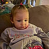 baby, blanket, casual, child, couch, cute, diaper_pack, expression, eyes, face, household, indoor, living_room, ponytail, portrait, seated, soft_lighting, sweater, toddler, toy