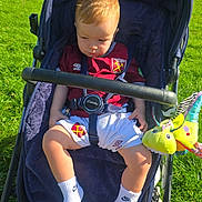 Boston joined the competition — help win amazing prizes! toddler, child, stroller, outdoor, park, grass, sunlight, west_ham_jersey, football, toy, plush, blue, white_socks, nike, footwear, baby_clothing, summer, daylight, person, casual