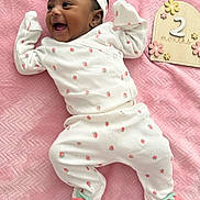 Evangeline is registered to the contest to win money with this photo: baby, infant, smiling, happy, white_clothing, headband, pink_blanket, strawberry_pattern, cute, newborn, milestone_sign, wooden_sign, flower_decor, lying_down, child, footwear, soft_texture, portrait, indoors, celebration