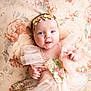 baby, infant, flower_crown, dress, floral, blanket, smile, cute, portrait, child, happy, soft_lighting, indoors, tulle, headband, hands, skin, closeup, laying_down, adorable