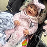 baby, baby_accessory, blanket, bunny_ears, child, clothing, cozy, cute, happy, headwear, indoor, infant, person, pink_outfit, playful, portrait, smiling, soft_texture, stroller, toy