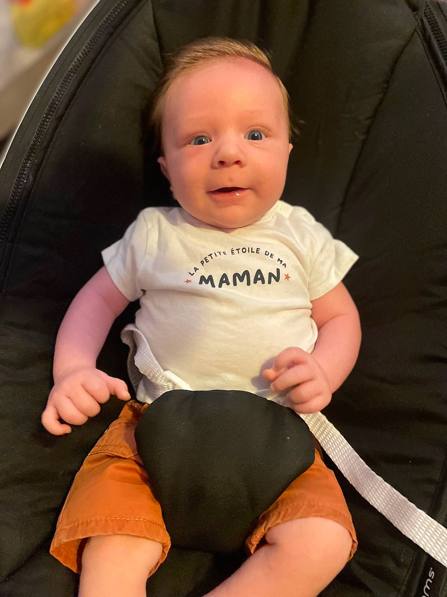 Ghjuvanni participe au concours pour gagner de l'argent avec cette photo : baby, baby_carriage, baby_toddler_clothing, black, chair, cheek, comfort, eye, finger, happy, knee, lap, orange, person, product, skin, sleeve, smile, thigh, toddler