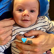 Milan a rejoint le concours — aidez-le/la à gagner de superbes lots ! baby, infant, smile, striped_onesie, blue_blanket, tattoo, wedding_ring, adult_hand, hands, big_eyes, close_up, portrait, indoor, cute, cuddling, emoji_heart, soft_fabric, person, face, holding