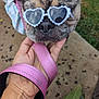 dog, brindle, sunglasses, heart_shaped, leash, hand, outdoor, grass, concrete, pet, canine, pink, accessory, close_up, animal, cute, relaxed, summer, portrait, fashion