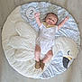 baby, infant, child, swan_mat, floor, white_outfit, brown_shoes, raised_arms, smiling, happy, indoor, soft_mat, cute, two_months, baby_bib, plush, patterned_mat, light_floor, baby_pose, baby_face