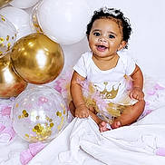 Journee is registered to the contest to win money with this photo: baby, child, tutu, balloons, gold, white, pink, smile, happy, celebration, curly_hair, sitting, cute, festive, portrait, clothing, face, infant, studio, background