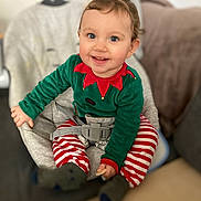 Luana a rejoint le concours — aidez-le/la à gagner de superbes lots ! toddler, child, baby, smiling, happy, blue_eyes, holiday_pajamas, striped_pants, green_top, baby_seat, cushion, indoor, cozy, home, blurred_background, cute, festive, clothing, person, portrait