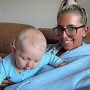 Ell joined the competition — help win amazing prizes! baby, blond_hair, casual_clothing, child, couch, cozy, face, glasses, happy, holding, home, indoor, light_blue, pajamas, parent_and_child, portrait, relaxing, seated, smile, woman