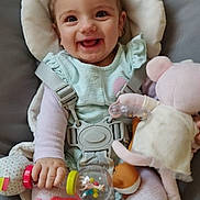 Mylana a rejoint le concours — aidez-le/la à gagner de superbes lots ! baby, child, smile, happy, toy, stuffed_animal, pigtails, seat_belt, baby_seat, cushion, infant, play, cute, indoors, clothing, hand, face, person, pink, colorful