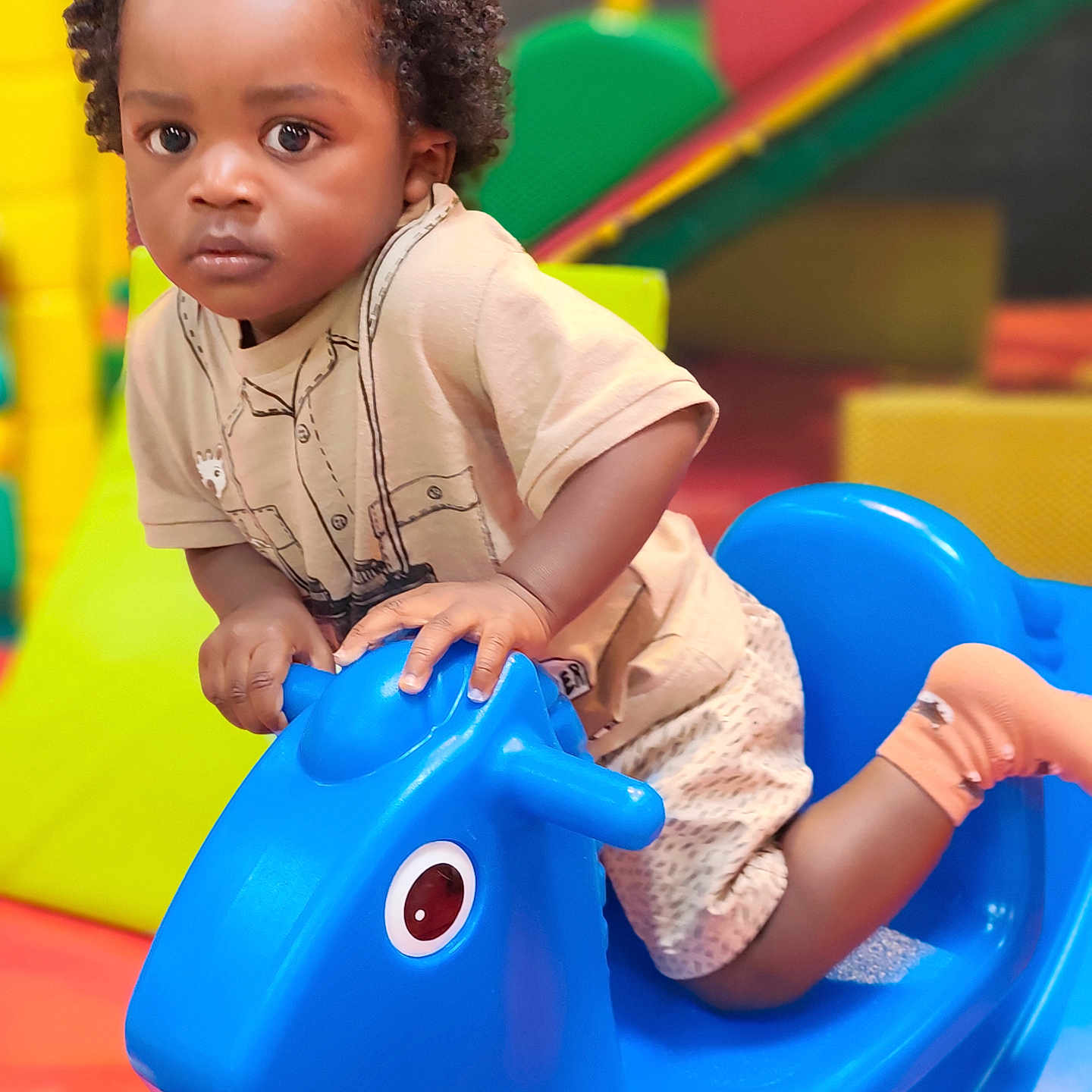 Shad a rejoint le concours — aidez-le/la à gagner de superbes lots ! background, blue, child, colorful, curly_hair, eyes, face, floor, hands, indoor, plastic, play_area, playground_equipment, rocking_horse, shirt, shorts, socks, toddler, toy, young_child