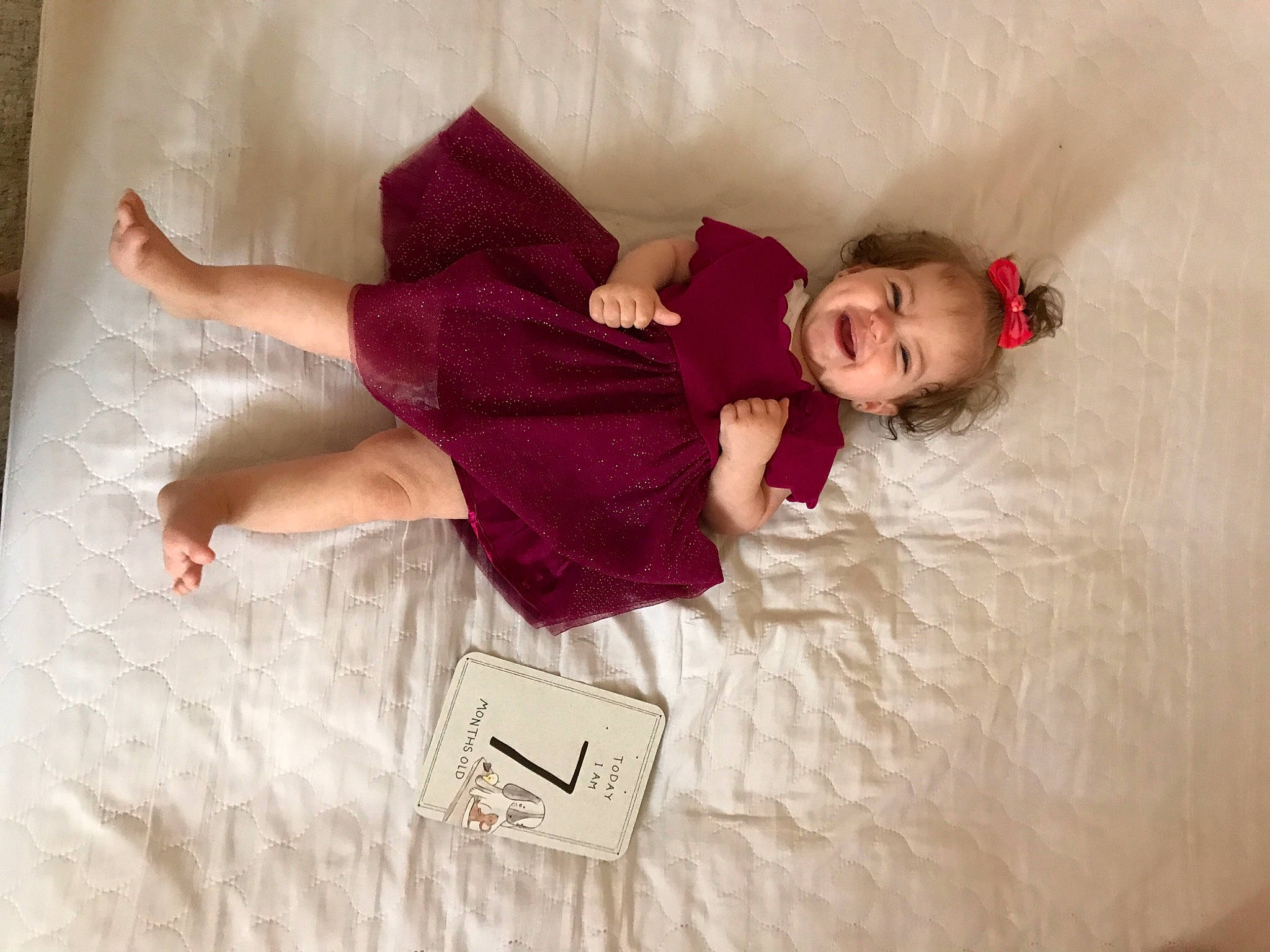 Erika is registered to the contest to win money with this photo: baby_toddler_clothing, bed, bedding, child, comfort, couch, floor, flooring, happy, human_body, leg, linens, magenta, mammal, person, pink, sleeve, sock, textile, thigh