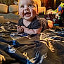 baby, smiling, indoor, blanket, dinosaur_pattern, couch, dog, toy, furniture, child, happy, cute, portrait, infant, living_room, clothing, person, face, colorful, home