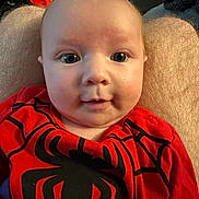 Hattie is registered to the contest to win money with this photo: baby, child, infant, face, eyes, red_clothing, spiderman_outfit, person, portrait, cute, indoor, human, legs, lap, expression, skin, hair, closeup, sitting, young