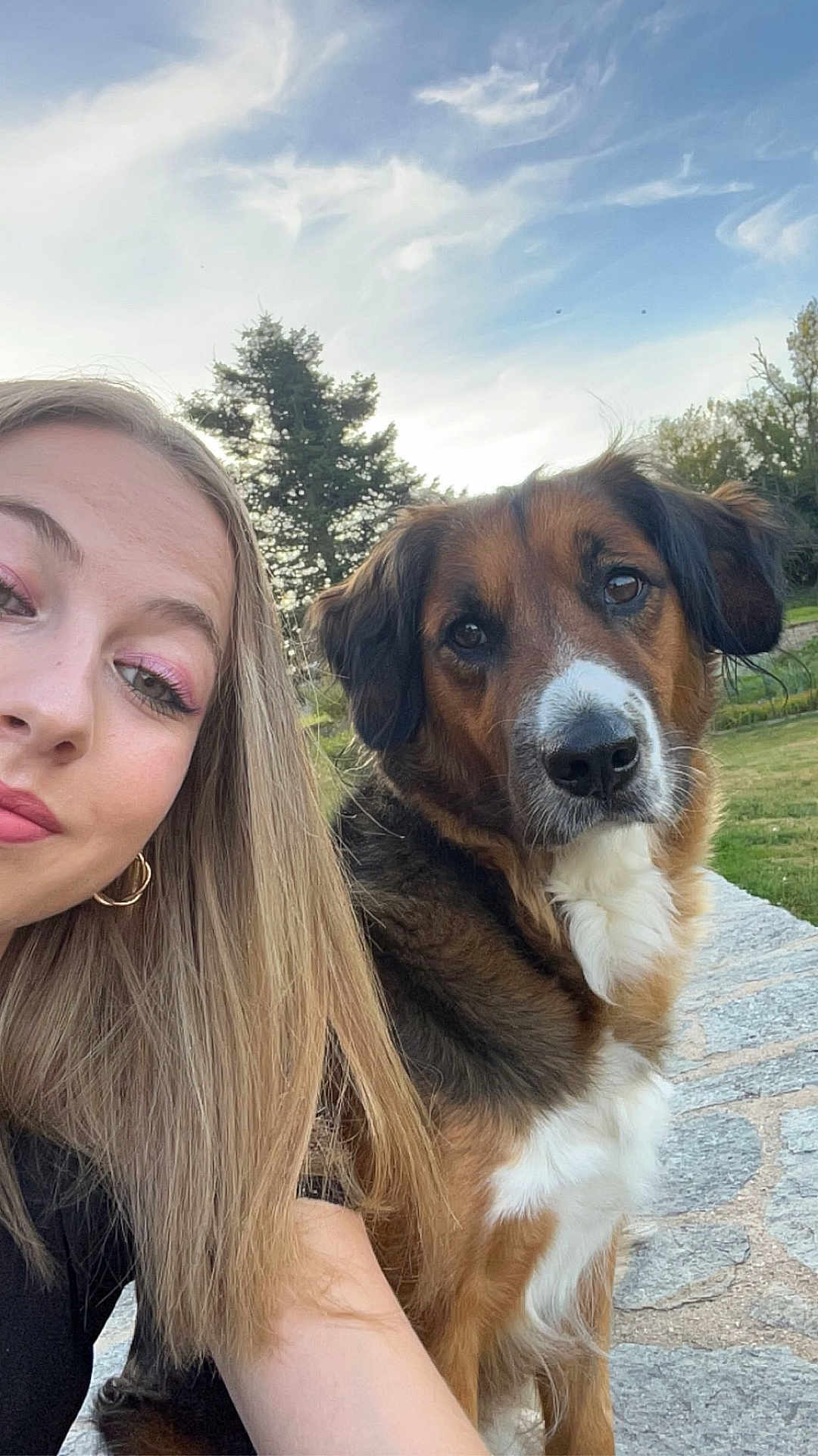 Perle participe au concours pour gagner de l'argent avec cette photo : dog, dog_face, person, woman, selfie, outdoor, sky, tree, grass, stone_surface, fur, portrait, ears, eyes, nose, gold_hoop_earring, makeup, smiling, park, bench
