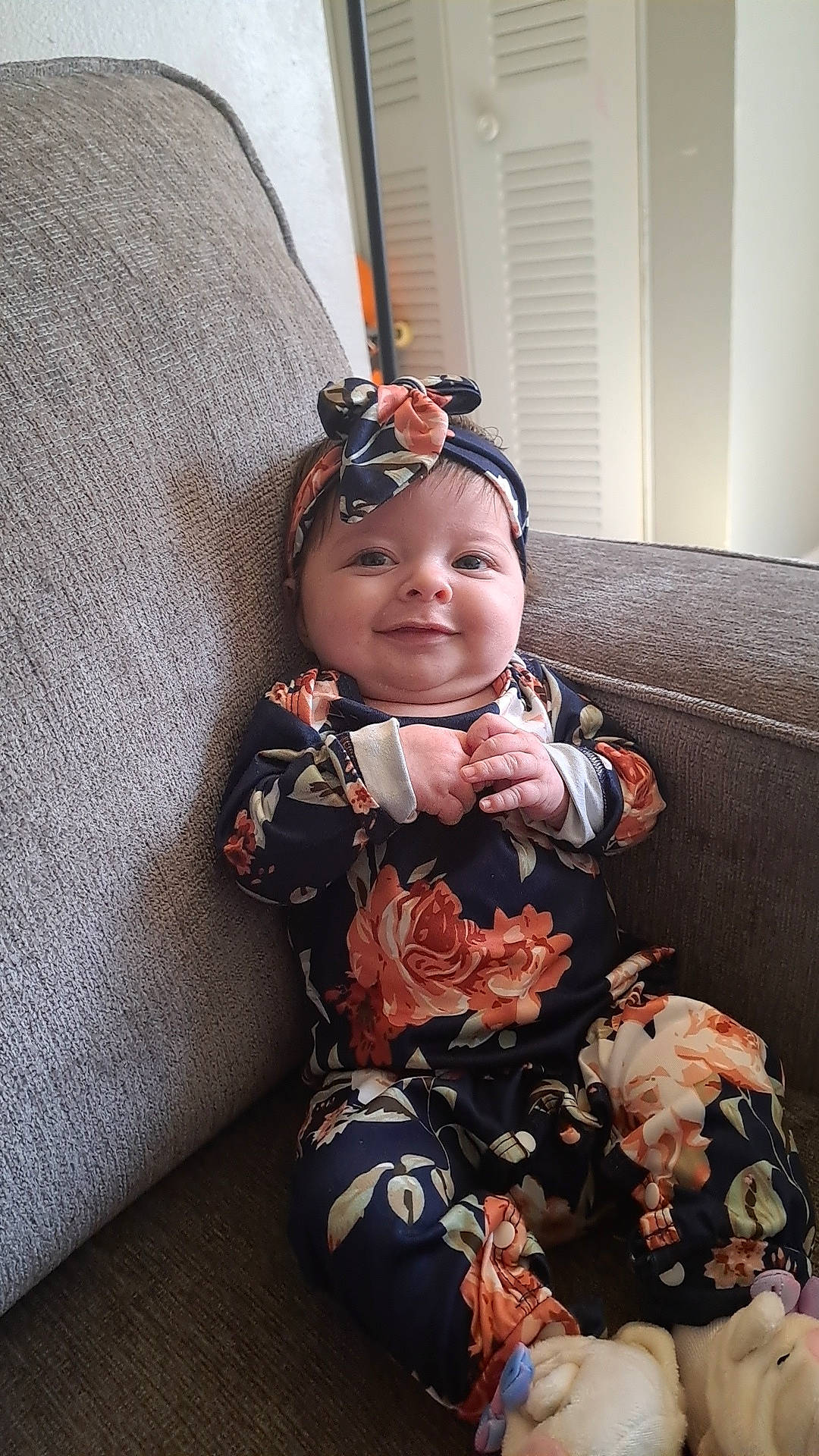 Journei Aliviah is registered to the contest to win money with this photo: baby, baby_toddler_clothing, comfort, couch, doll, dress, eye, face, flooring, happy, head, headwear, human_body, joy, outerwear, pattern, person, personal_protective_equipment, sitting, sleeve
