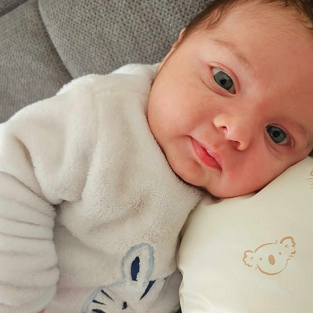 Ylio a rejoint le concours — aidez-le/la à gagner de superbes lots ! baby, bunny_design, child, comfort, couch, cozy, cute, eyes, face, head, indoors, infant, lying_down, person, pillow, resting, skin, sleepy, soft_texture, white_clothing