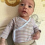 baby, infant, child, striped_shirt, beige_pants, play_mat, lion_pattern, elephant_pattern, floor_mat, cute, lying_down, indoors, young_child, person, small_hand, curious_expression, close_up, head, face, skin