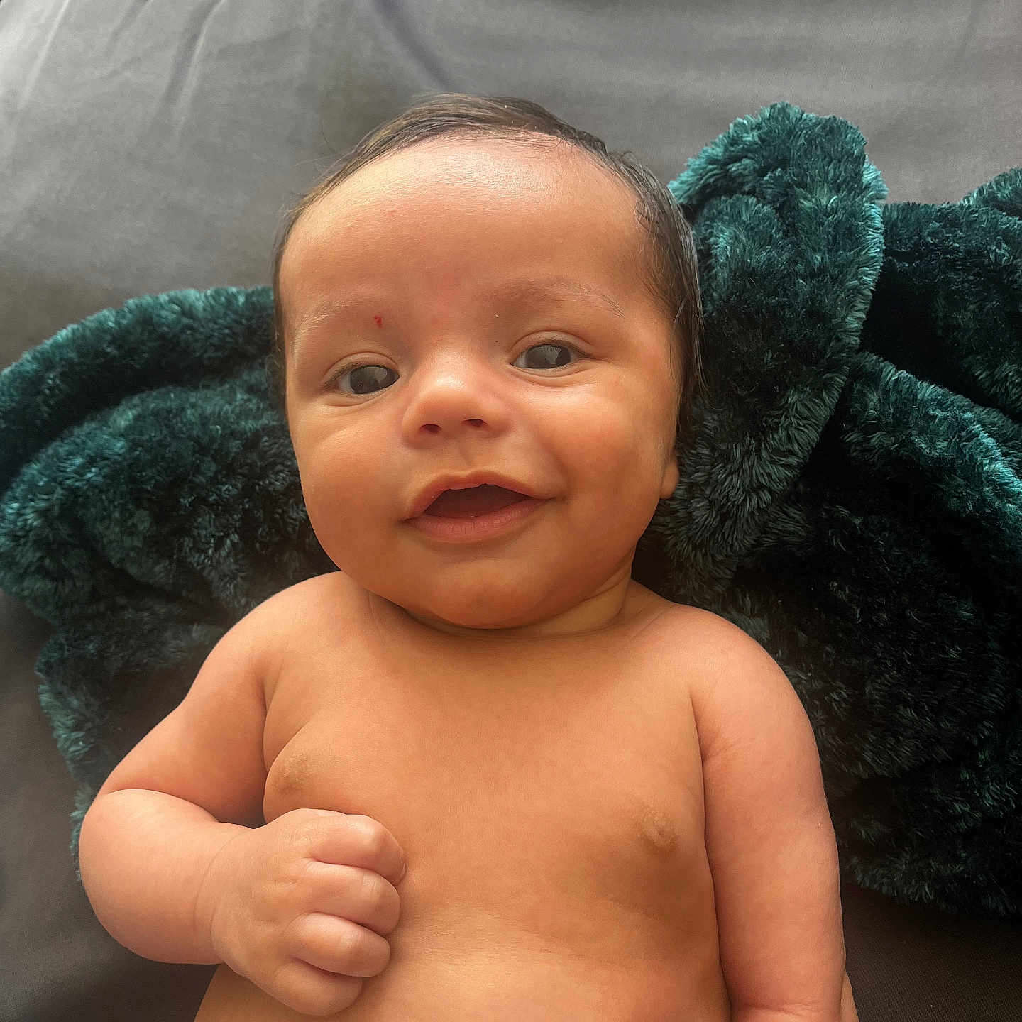 Wesley is registered to the contest to win money with this photo: baby, blanket, bodypart, cushion, face, finger, hand, happy, head, homedecor, laughing, mouth, newborn, person, photography, portrait, sitting, smile, teeth, towel