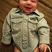 Walker is registered to the contest to win money with this photo: baby, infant, smiling, denim_shirt, clothing, cute, chubby_legs, lying_down, happy, face, hand, buttoned_shirt, textured_blanket, casual, portrait, child, skin, indoor, small_person, adorable