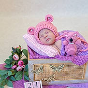 Gloria a rejoint le concours — aidez-le/la à gagner de superbes lots ! baby, sleeping, pink_hat, crochet, basket, blanket, teddy_bear, flowers, wooden_butterflies, cozy, soft_lighting, newborn, cute, decor, portrait, indoor, peaceful, child, knitted, resting