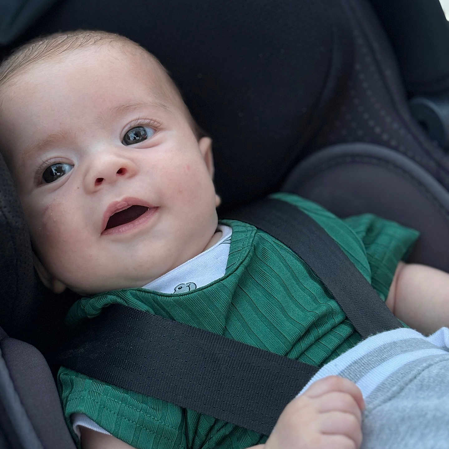 Kelio participe au concours pour gagner de l'argent avec cette photo : baby, baby_boy, car_seat, child, closeup, clothing, cute, eyes, face, green_shirt, hand, indoors, infant, person, portrait, safety, seat, seatbelt, smiling, young