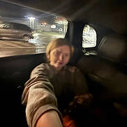 Miley joined the competition — help win amazing prizes! person, selfie, blurry, night, car_interior, parking_lot, window, lights, short_hair, arm, casual_clothing, dark, reflection, vehicle, headrest, urban, street_lighting, motion_blur, indoors, seat