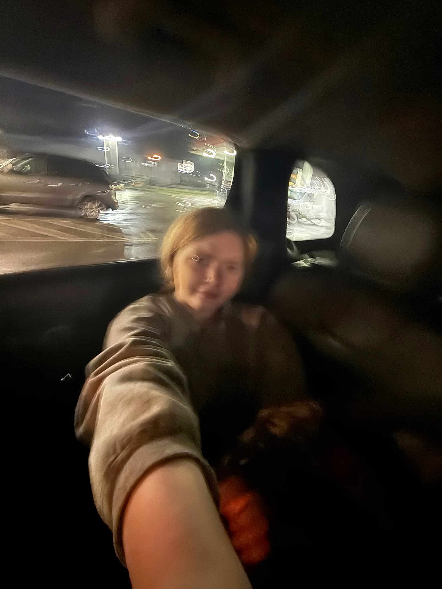 Miley joined the competition — help win amazing prizes! person, selfie, blurry, night, car_interior, parking_lot, window, lights, short_hair, arm, casual_clothing, dark, reflection, vehicle, headrest, urban, street_lighting, motion_blur, indoors, seat