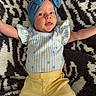 Lennon joined the competition — help win amazing prizes! arms_outstretched, baby, black_and_white, blue, bow, child, clothing, cute, floral_pattern, headband, indoor, infant, lying_down, patterned_rug, person, playful, portrait, rug, striped_shirt, yellow_pants